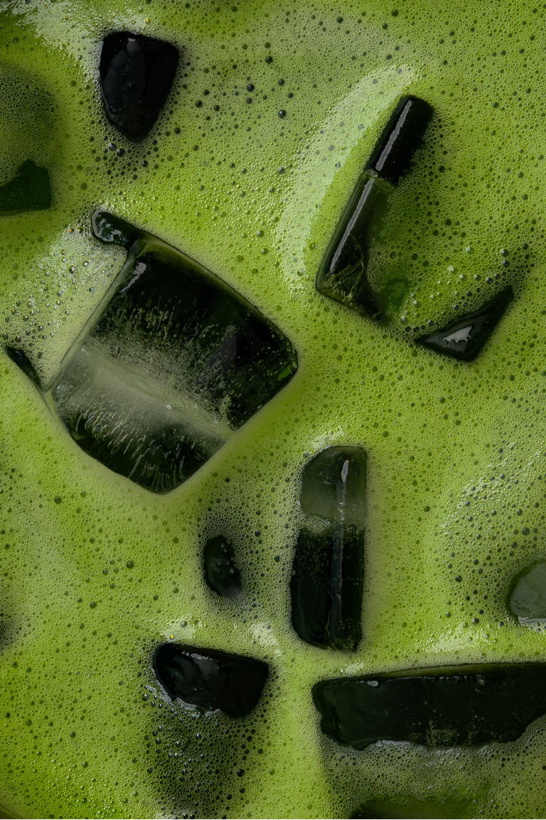 Close-up of iced green beverage with black ice cubes